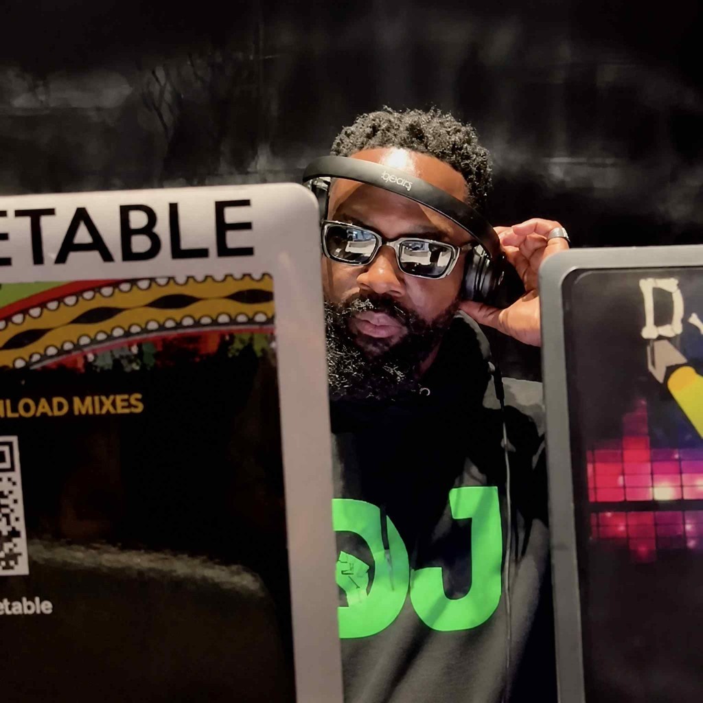 DJ Unbeetable at the booth in headphones and sunglasses